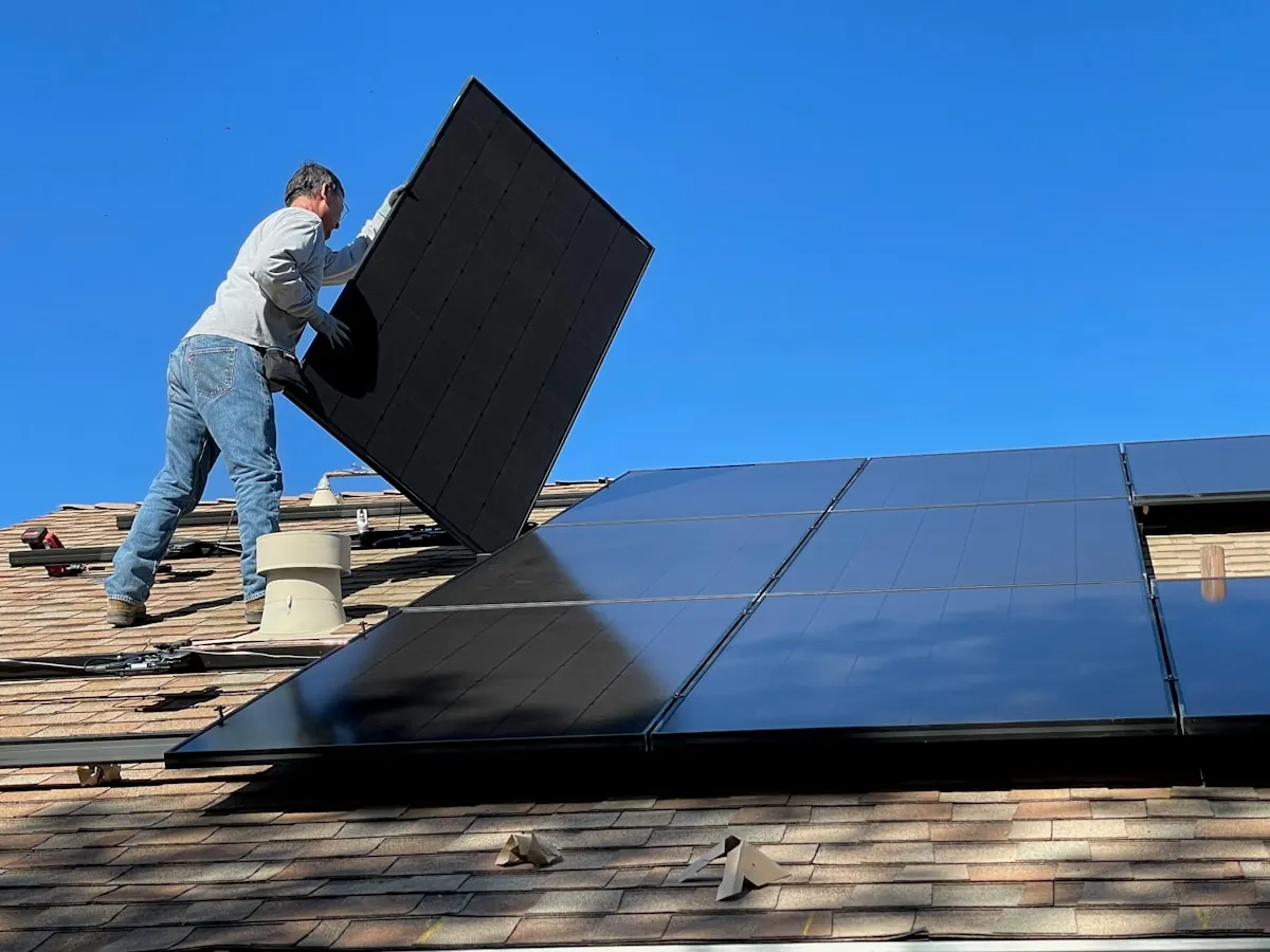 Instalator montând panouri fotovoltaice pe un acoperiș rezidențial